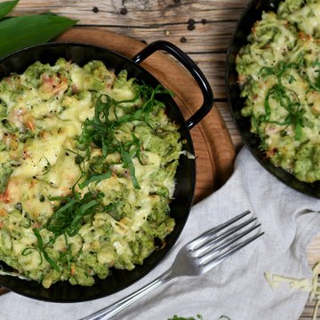 Bärlauchspätzle mit Almkönig und Schinken angerichtet in einer gusseisernen Pfanne